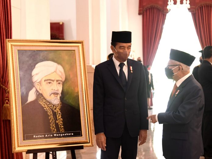 FOTO: Presiden Jokowi berbincang dengan Wakil Presiden Ma’ruf Amin di depan lukisan Raden Aria Wangsakara, Pahlawan Nasional dari Banten, yang baru saja dianugerahkan pada Rabu (10/11/2021). (Foto: BPMI Setpres/Rusman)