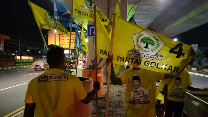 FOTO: Sejumlah orang menggunakan baju bergambar Ilham Arief Sirajuddin Sedang memasang bendera partai golkar di dibawa kolong tol layang AP. Pettarani. Jumat (27/5) malam.