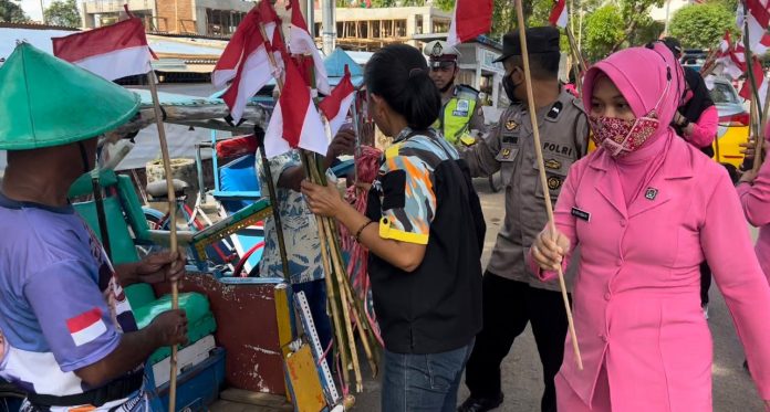 FOTO: Pengurus Bhayangkari Ranting Turikale, Hj Asma Mustamin dan Ketua Distrik GMBI Distrik Maros saat membagi bendera merah putih ke para tukang becak di pusat kota Maros. Selasa, (16/8/2022)