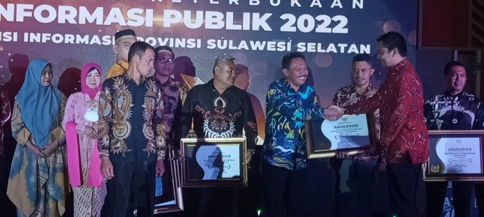 FOTO: Kepala Desa Bira Murlawa saat menerima penghargaan yang diserahkan oleh Wakil Ketua KI Pusat, Arya Sandhiyudha pada acara Penganugerahan Keterbukaan Informasi Publik, yang berlangsung di Ballroom Sandeq Hotel Claro Makassar, Jumat malam, 2 Desember 2022.