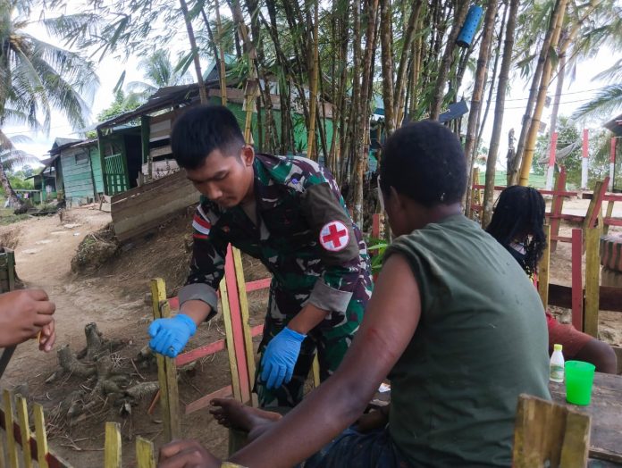 FOTO: Anggota Satgas Pamtas Yonif 132/BS Pos Skamto saat mengobati warga Kp.Yowong akibat kecelakaan tunggal.