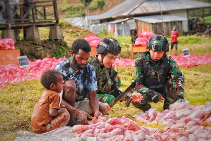 FOTO: Satgas Yonif Raider 321/GT/13/1 Kostrad bersama masyarakat melaksanakan kegiatan bakar batu dan membagikan ratusan bungkus bahan makanan untuk masyarakat di Distrik Mbua, Kab. Nduga, Papua (21/12/22).