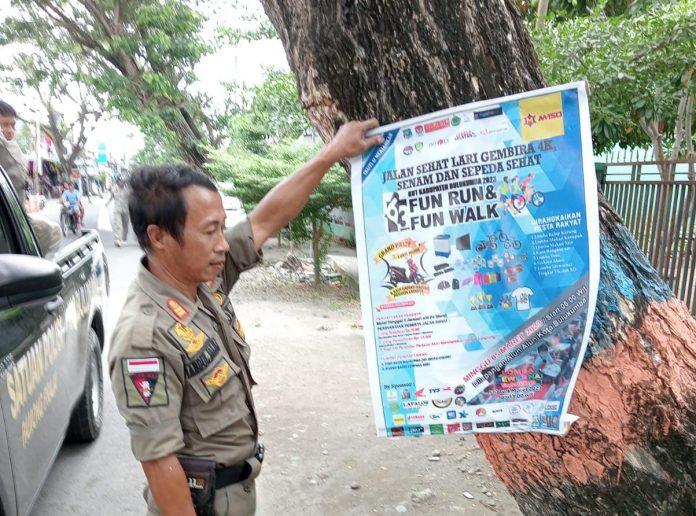 FOTO: Salah satu anggota Satuan Polisi Pamong Praja dan Pemadam Kebakaran (Satpol PP dan Damkar) Kabupaten Bulukumba, melakukan penertiban baliho di wilayah kota kabupaten, Selasa, 27 Desember 2022.