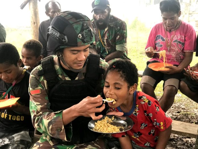 FOTO: Salah satu personil Satgas Yonif Raider 321/GT/13/1 Kostrad Pos Yigi makan bersama dengan Masyarakat, bertempat di Kampung Yigi, Distrik Yigi, Kabupaten Nduga, Papua. Senin (9/1/2023)