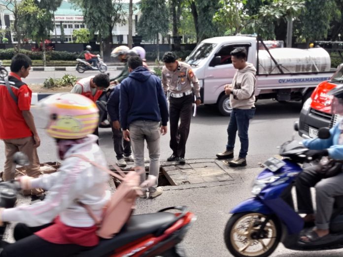 FOTO: Anggota Kepolisian dari satlantas saat berada di TKP Lubang Drainase Maut di Jalan Urip Sumoharjo Kota Makassar diantar SPN dan Dealer Honda Batua. (Dok. Warga Makassar)