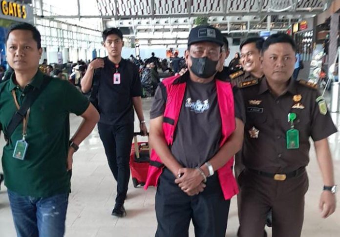 FOTO: Boni Tabrani Bin Sastra gunakan Topi saat diamankan Tim Tabur Kejati Sulsel dan Kejari Bone saat tiba di Bandara Sultan Hasanuddin Makassar.