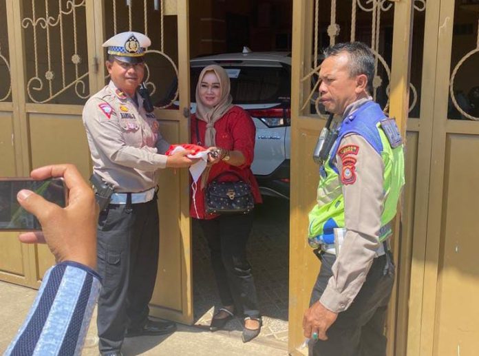 FOTO: Kanit Turjawali IPDA Hamsal Hamid SH, bersama personil Satlantas Polres Gowa saat membagi bendera ke warga di kecamatan Palangga. Rabu (16/8)