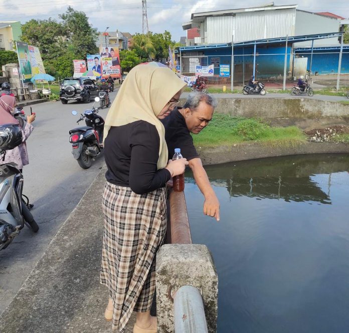 FOTO: Kanan berhijab Ratna Raki Caleg Partai Golkar bersama komunitas Makassar Tanpa Sekat menuangkan cairan ekoenzim di aliran waduk Pampang, Toddopuli, Kecamatan Panakkukang, Makassar. Sabtu (30/12/2023)