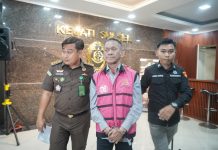 Kejati Sulsel Tahan Kontraktor Proyek Pembangunan Perpipaan Air Limbah Kota Makassar Zona Barat Laut FOTO: Kepala Seksi Penerangan Hukum (Kasi Penkum) Kejati Sulsel, Soetarmi saat membawa Direktur Utama PT. Karaga Indonusa Pratama, TGS saat akan dibawa ke mobil tahanan. Selasa (8/4/2025).