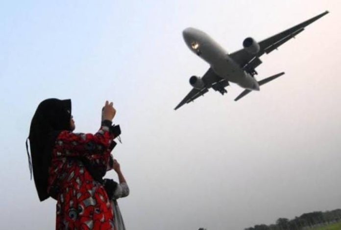 FOTO: Ilustrasi warga melihat pesawat hendak melakukan landing. (Properti via Google)