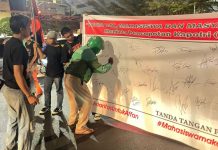Aksi Mahasiswa di Makassar Berujung Petisi Copot Kapolri FOTO: Salah seorang pengemudi ojek online di kota Makassar saat membumbui tandatangan petisi copot Kapolri oleh aktivis Gerakan Aksi Mahasiswa. (Istimewa)