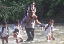 Bentuk Satgas Jembatan, Presiden Perintahkan Menteri Dikti Siapkan Mahasiswa Teknik Sipil untuk ke Desa Desa FOTO: Aipda Ismet Ishak saat membantu para pelajar menyeberangi sungai di wilayah pelosok di provinsi Gorontalo. (Properti via Google)