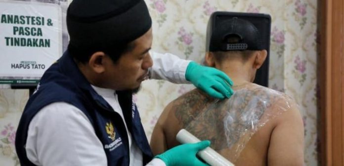 FOTO: Seorang profesional sedang membersihkan tatto. (Dok via Google)